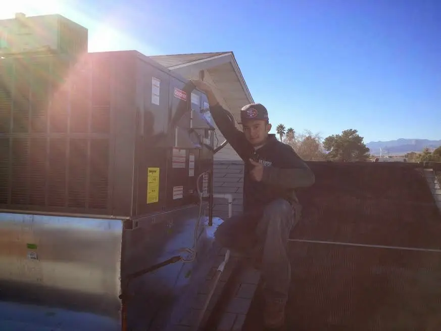 HVAC technician performing AC Tune-Up on a rooftop unit in Walker