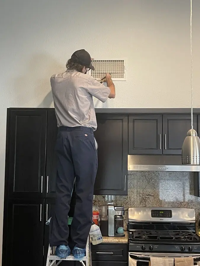 Technician inspecting an air vent during HVAC service in Walker
